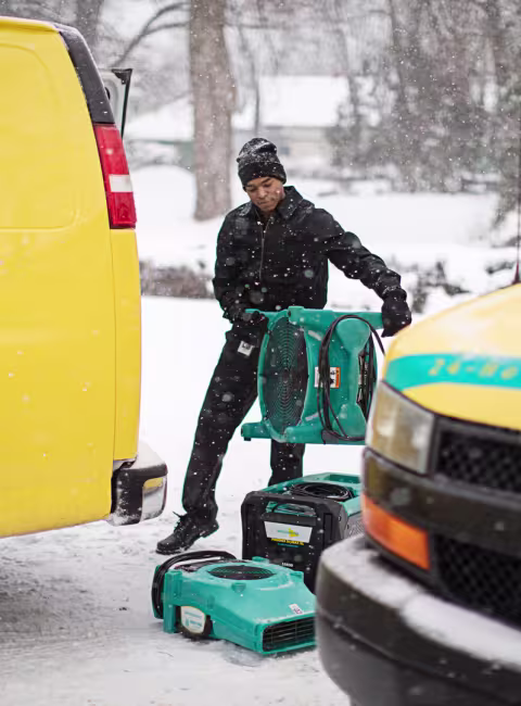 winter water damage technician with equipment and yellow vans