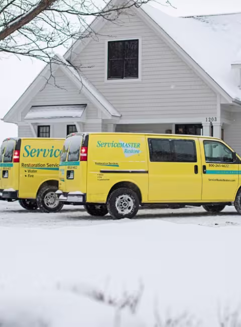 ServiceMaster Restore trucks parked outside a house during a snow storm