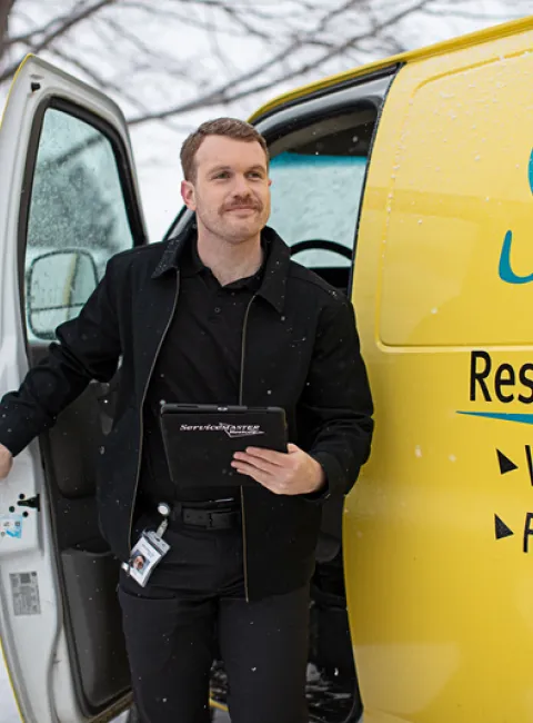 ServiceMaster technician getting out of yellow service van