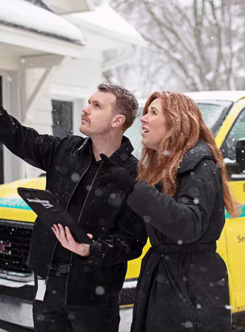 technician and homeowner inspecting exterior home winter damage
