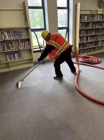 water damage technician extracting carpet in library 