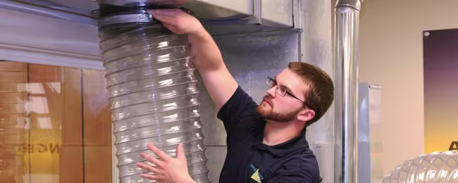 Technician hooking air duct cleaning vacuum to ductwork