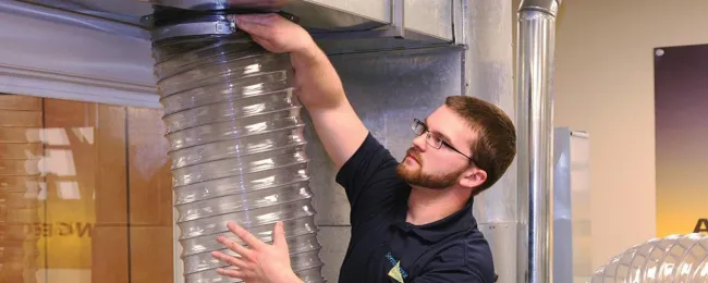 Technician hooking air duct cleaning vacuum to ductwork