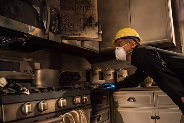 ServiceMaster technician inspecting underside of kitchen cabinets post fire