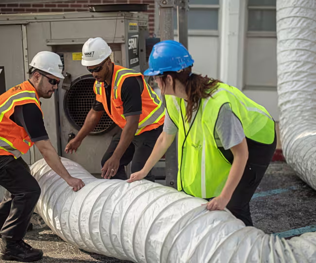 servicemaster restore technicians lifting a large scale water extraction hose