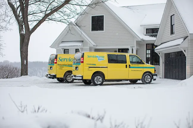 ServiceMaster Vans in Winter. Parked in snowy drive outside of a residence.