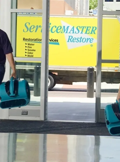Two ServiceMaster Fire & Water Cleanup technicians enter a commercial building in Chicago to begin restoration services