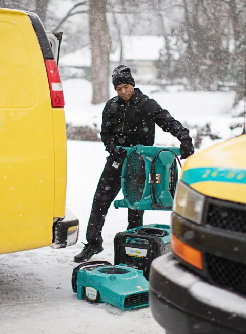 winter water damage technician with equipment and yellow vans