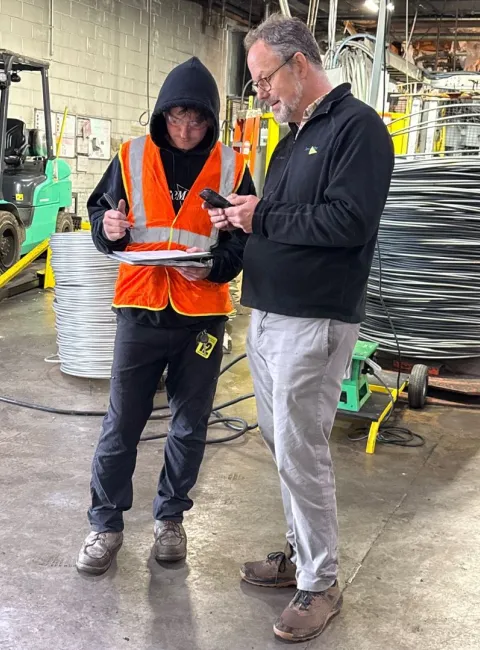 Two guys one in an orange vest on a jobsite