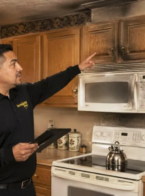 ServiceMaster technician discussing the smoke damage cleanup process to a homeowner while standing in a smoke damaged kitchen