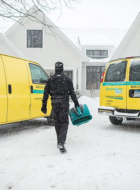 servicemaster restore technician carrying an industrial dryer into a home