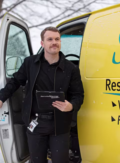 ServiceMaster technician getting out of yellow service van