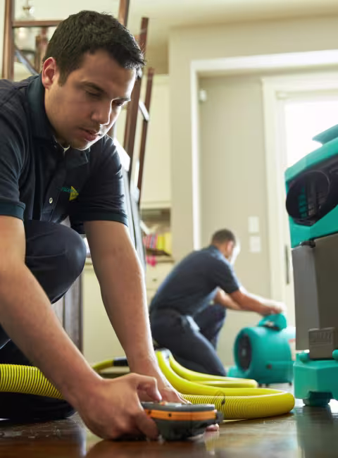 ServiceMaster tech performing water damage restoration in a home