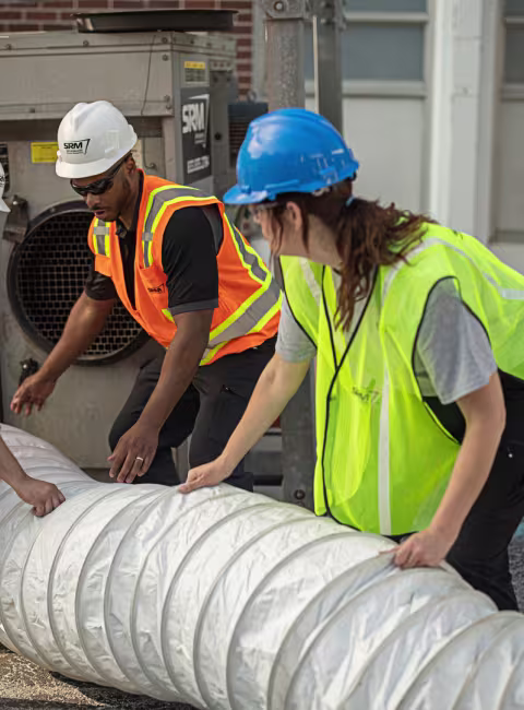 servicemaster restore technicians lifting a large scale water extraction hose