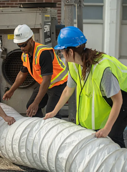 servicemaster restore technicians lifting a large scale water extraction hose