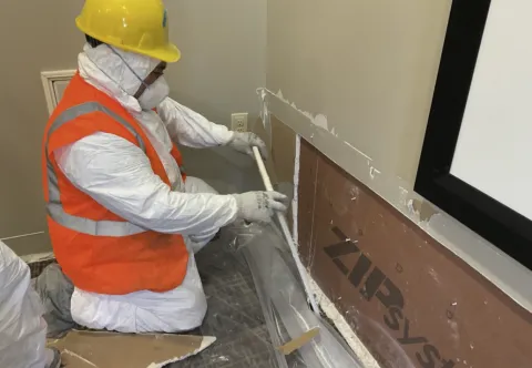 water damage tech demoing wall