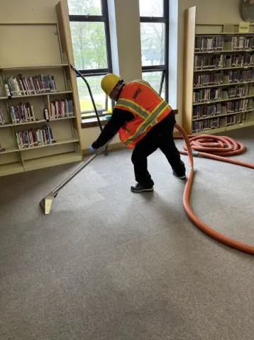 water damage technician extracting carpet in library 