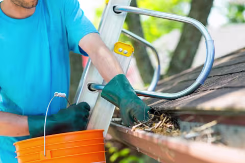 Gutter full of debris being cleaned out to prevent overflow