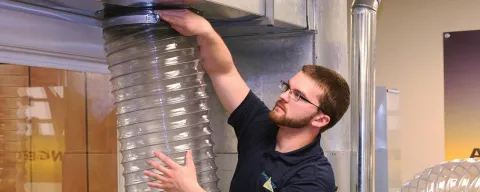 Technician hooking air duct cleaning vacuum to ductwork