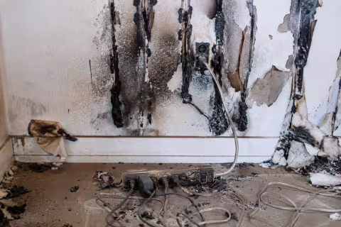 Fire damaged electrical power strip and wall with charring and paint peeling