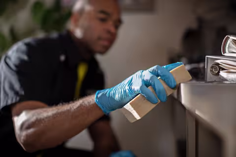 ServiceMaster technician using a rubber sponge to wipe soot off of a desk