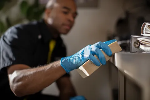 ServiceMaster technician using a rubber sponge to wipe soot off of a desk
