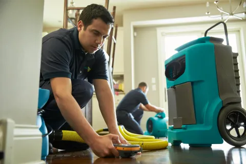 ServiceMaster tech performing water damage restoration in a home