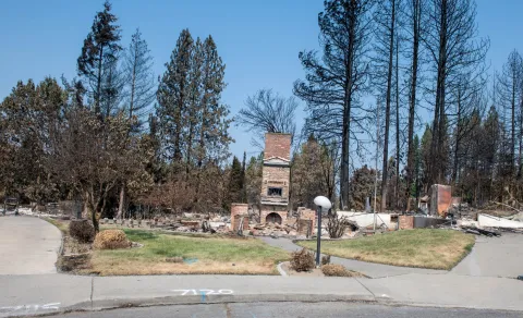 Chimney left standing among wildfire debris in a Spokane neighborhood