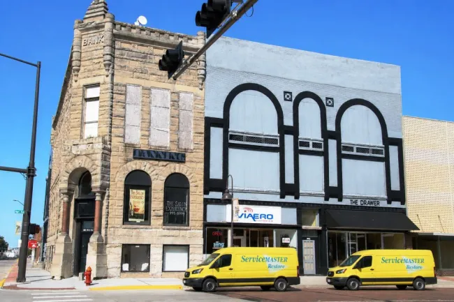 Two yellow, servicemaster vans in front of commercial buildings in downtown Holdrege