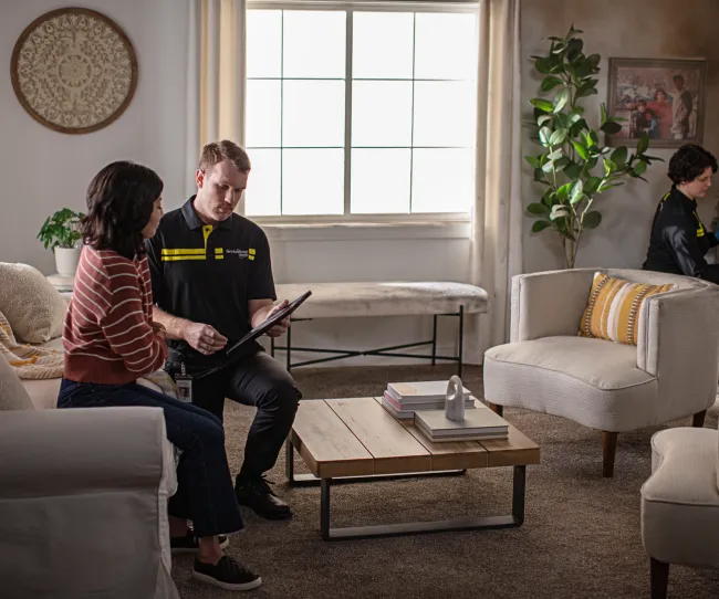 servicemaster tech and customer discussing fire damage in a living room