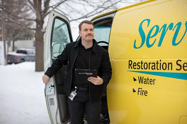 ServiceMaster technician getting out of yellow service van