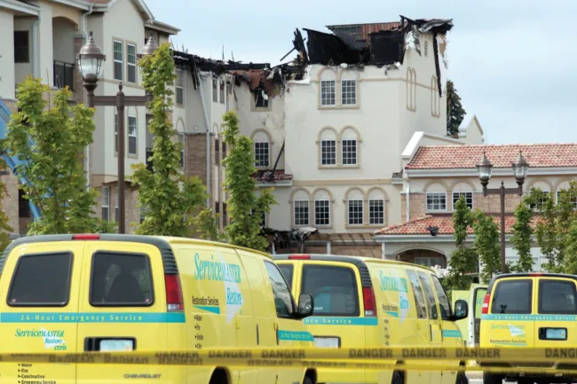 behind-pov-of-a-fleet-of-servicemaster restore vans heading for a weather damaged hotel