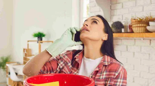 woman gathering water with leaky roof