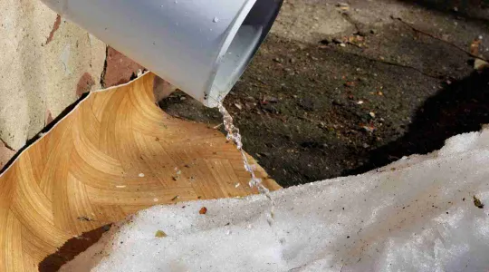 snow melt coming down a spout at a house