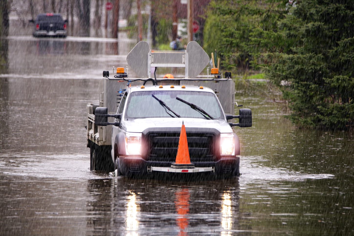 A truck is driving through rain and a flooded street